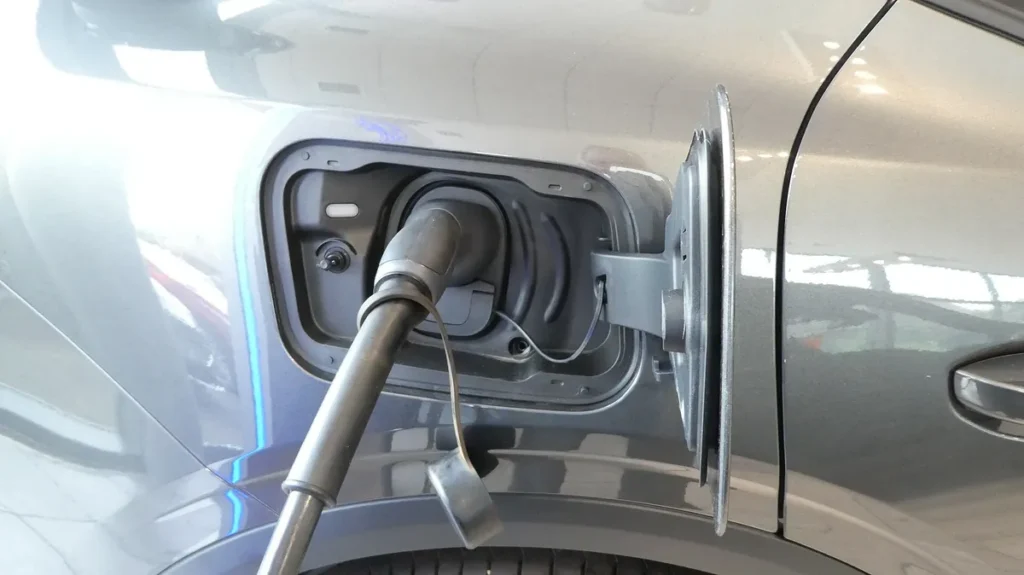 Charging cable plugged into the charging port of a grey electric car